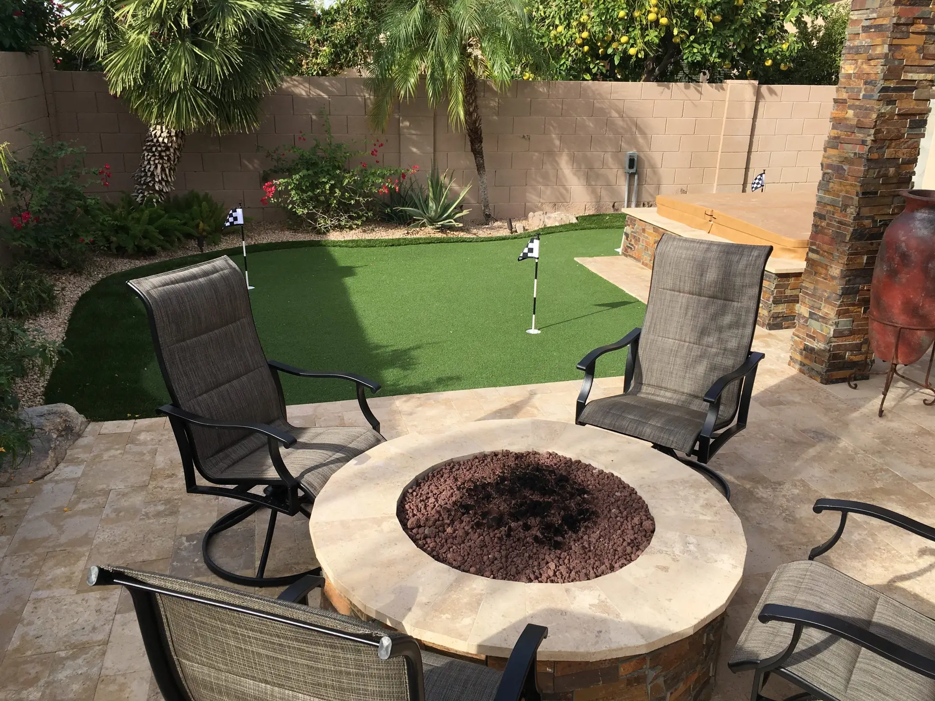 Custom putting green and fire pit area with artificial turf and lounge chairs.