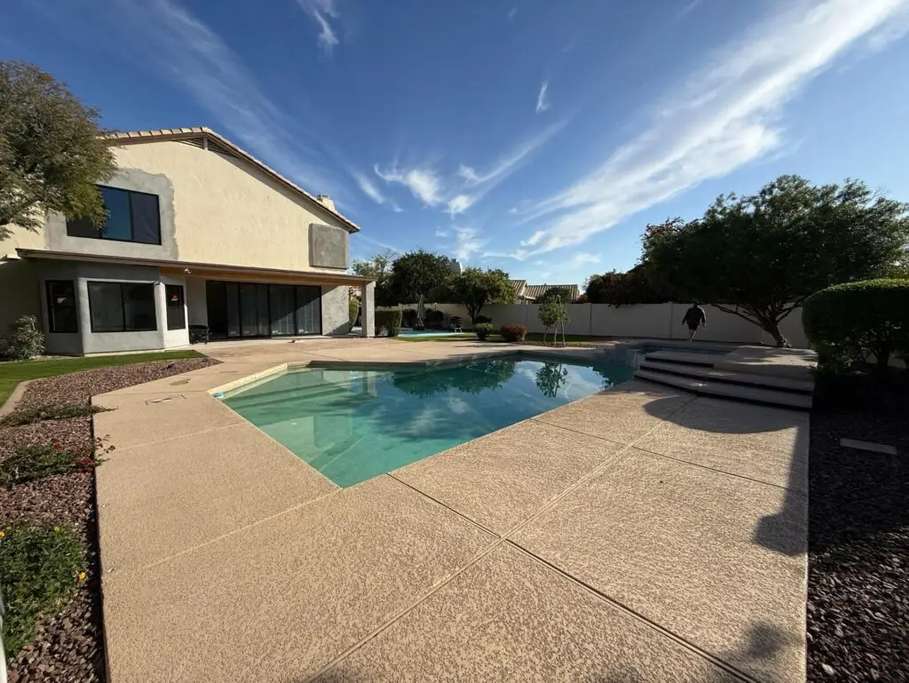 Backyard remodel in Chandler, AZ, featuring a swimming pool, landscaped garden, and modern home exterior with natural stone accents.