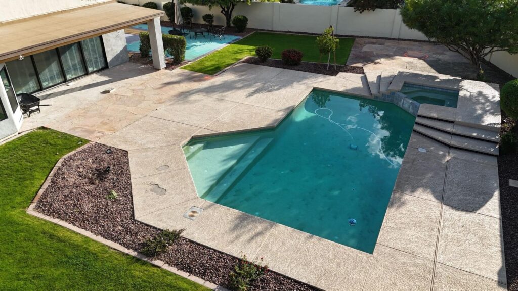 Backyard remodel in Chandler, AZ, featuring a polished travertine patio, a swimming pool with a spa, and landscaped greenery, designed for family gatherings and outdoor enjoyment.