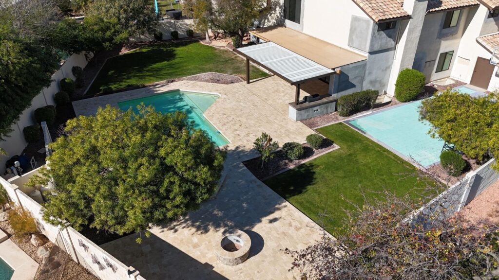 Backyard remodel in Chandler, AZ featuring travertine patio, pergola, lush green lawn, and swimming pool, designed for family gatherings and outdoor enjoyment.