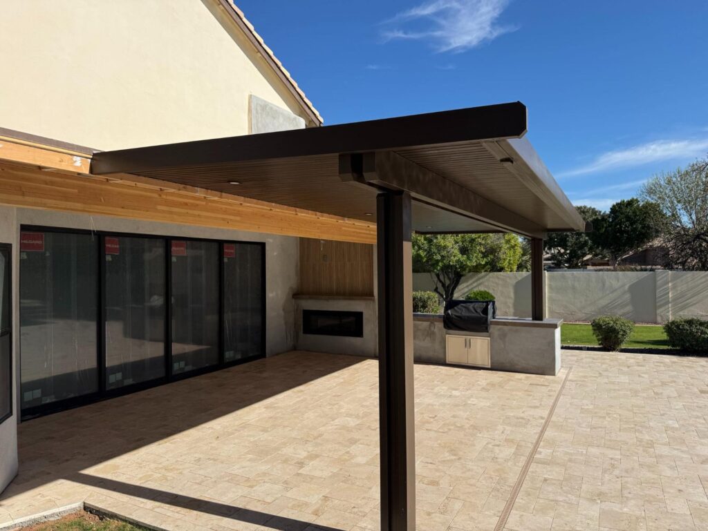 Backyard remodel in Chandler, AZ featuring a modern pergola, travertine flooring, and outdoor kitchen, designed for family gatherings and relaxation.