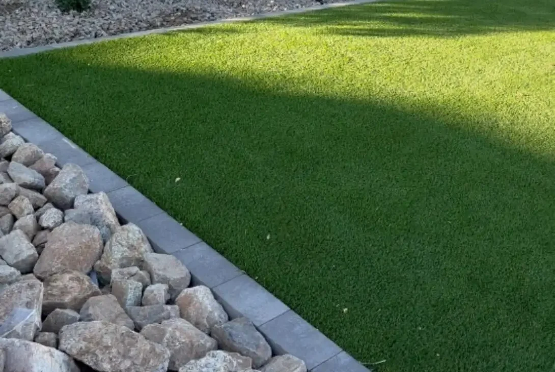 Artificial turf lawn with concrete pavers and decorative rocks, showcasing a modern backyard remodel in Gilbert, AZ, enhancing outdoor aesthetics.