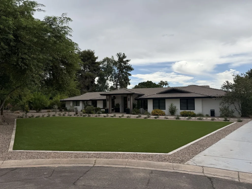 Street view of a modern Phoenix, AZ home with a new artificial turf front lawn, travertine border and desert plantings